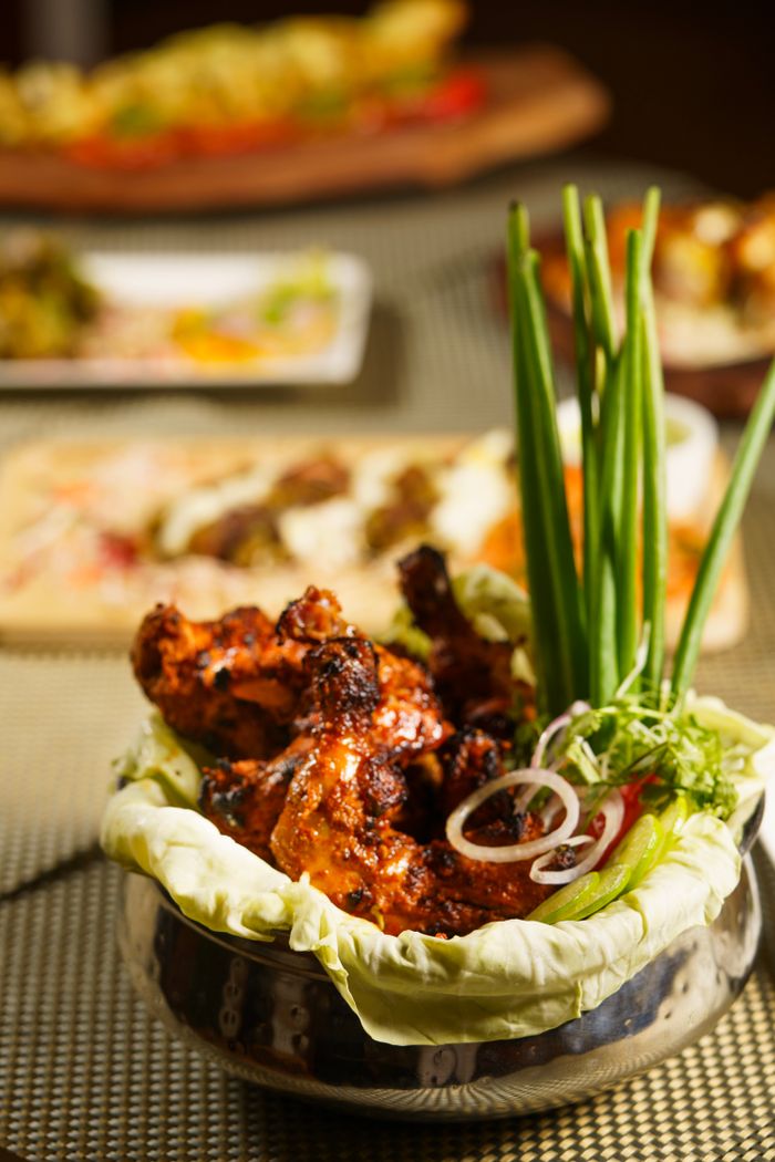 Delicious tandoori chicken served with fresh herbs and onions in a decorative setting.