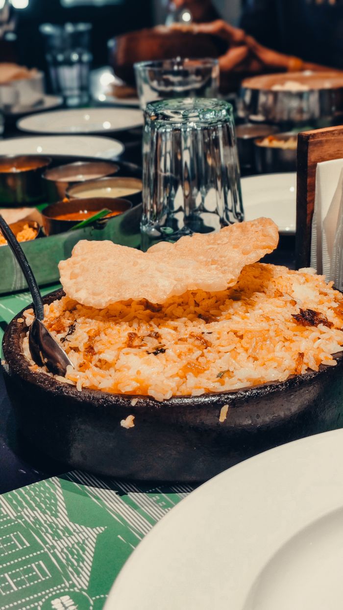 Close-up of a flavorful Indian biryani served with crispy papadum on a table setting.